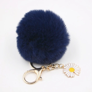Détail du porte-clés pompon bleu marine avec breloque marguerite blanche et fermoir mousqueton doré