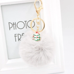 Gros plan d'un porte-clés pompon gris clair avec pendentif sapin de Noël vert