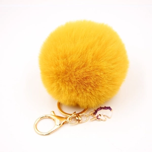 Detailed view of ginger yellow fluffy fur pompom with golden unicorn enamel keychain charm