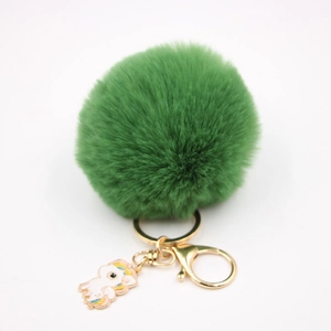 Détail d'un porte-clés pompon vert en fausse fourrure avec breloque licorne et fermoir doré
