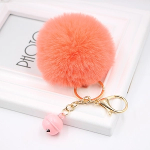 Close-up of fluffy orange faux fur keychain with gold ring and a pink jingle bell detail