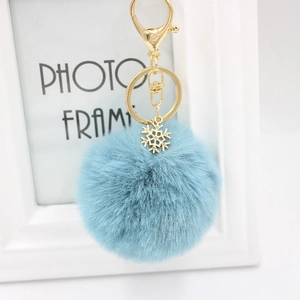 Close-up of light blue fluffy keychain with golden snowflake charm and metal lobster clasp
