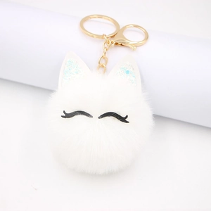Cute white pom-pom cat keychain with sparkling ears and golden clasp on white background