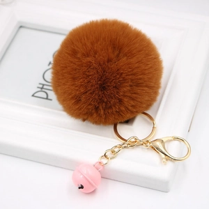Detail of plush brown faux fur keychain with a small pink bell on white frame