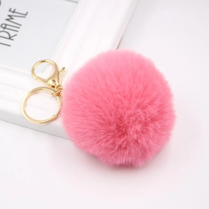 Close-up of pink faux rabbit fur pompom keychain with golden metal lobster clasp