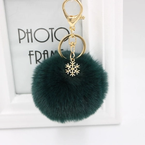 Detail of dark green plush pompom keychain with a golden snowflake charm and ring
