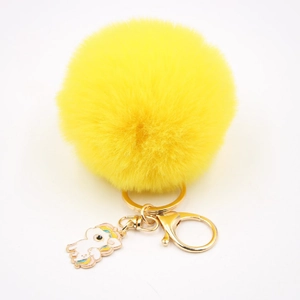 Détail d'un porte-clés licorne en fourrure jaune avec mousqueton doré pour sac à main