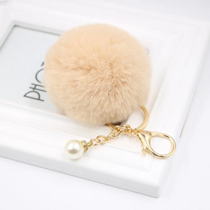 Detail of soft beige faux fur pompom keychain with gold lobster clasp and pearl