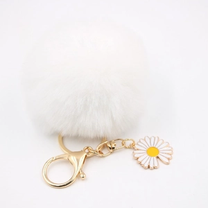 Détail d'un porte-clés marguerite blanche à pompon avec fermoir doré et breloque fleur