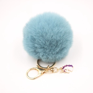 Close-up of a light blue faux fur pompom keychain with a gold unicorn charm and lobster clasp