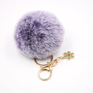 Détail du porte-clés pompon violet avec fermoir doré et charme flocon de neige vert