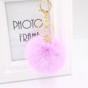 Detail of light purple faux fur keychain with a gold snowflake pendant and clasp