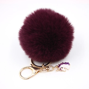 Detail of deep purple fluffy faux fur pompom keychain with gold unicorn charm pendant