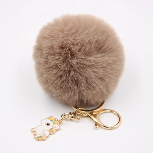 Détail du porte-clés pompon marron en fausse fourrure avec breloque licorne