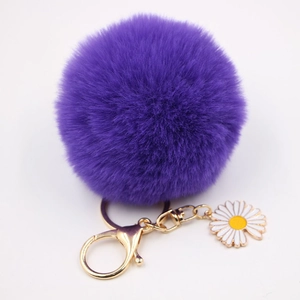 Vue détaillée d'un porte-clés pompon violet avec un pendentif marguerite émaillé
