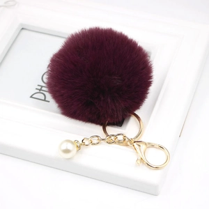Detail of luxury deep purple faux fur pompom keychain with gold hardware and pearl charm