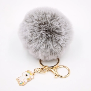 Détail du porte-clés pompon en fourrure grise avec breloque licorne et métal doré