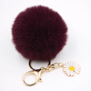 Détail du porte-clés pompon violet foncé avec fermoir doré et breloque marguerite