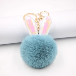 Dettaglio portachiavi a forma di coniglio in peluche blu con orecchie e gancio dorato