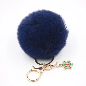Détail macro du porte-clés pompon en fausse fourrure bleu marine et flocon doré