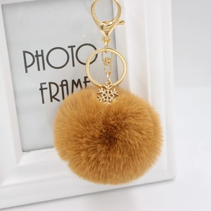 Detailed macro view of the fluffy brown faux fur pompom and golden snowflake charm