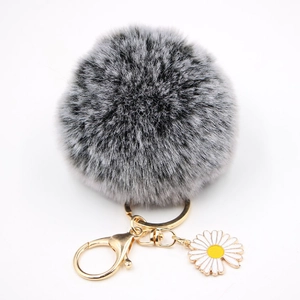 Détail du porte-clés pompon en fourrure dégradé gris avec pendentif marguerite dorée