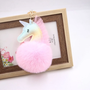 Détail d'un porte-clés licorne en pompon rose avec corne arc-en-ciel et fermoir doré