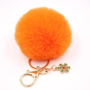 Détail d'un porte-clés pompon orange avec flocon de neige doré et gemme rouge éclatante