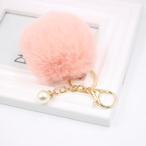 Close-up of pink faux fur keychain with golden lobster clasp and white pearl charm