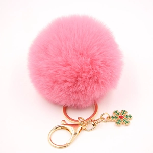 Détail d'un porte-clé pompon rose avec fermoir doré et charm flocon de neige