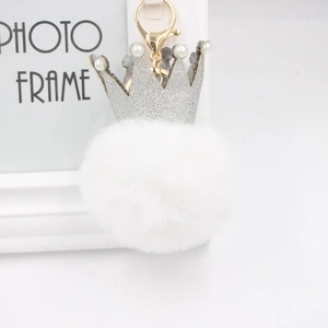 Détail d'un porte-clés pompon blanc avec couronne à paillettes argentées et perles