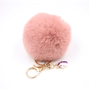 Detailed close-up of pink faux fur pompom keychain with golden clip and unicorn charm