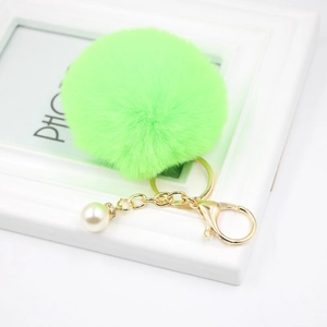 Close-up of fluffy lime green fur keychain with golden clasp and pearl detail