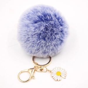 Détail d'un pompon en fausse fourrure violette avec breloque marguerite dorée et fermoir