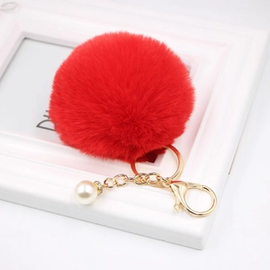 Detailed close-up of a fluffy red faux fur ball keychain with gold clasp and pearl charm