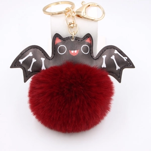 Halloween bat plush pompom keychain with red faux fur and black wings on white base
