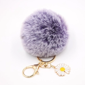 Détail du porte-clés pompon en fausse fourrure violette avec fermoir doré et pendentif marguerite