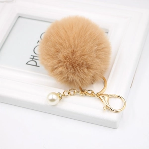 Detail of soft khaki faux fur pompom keychain with golden lobster clasp and pearl accent