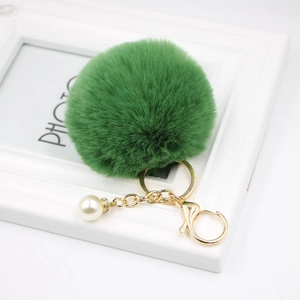 Detail of green faux fur pompom keychain with gold lobster clasp and pearl charm