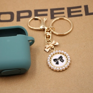 Elegant gold alloy keychain with pearl-edged bow pendant on a paper background
