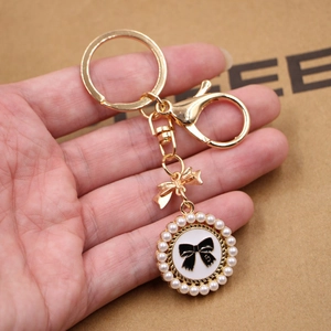 Golden keychain with pearl-beaded circular pendant featuring a bow and number 5 design