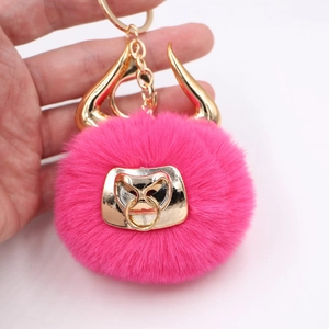 Macro shot of fluffy rose red faux fur keychain with golden bull horns and metal nose ring