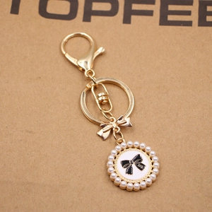Elegant golden keychain with pearl circular pendant and stylish bowknot design