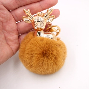 Détail d'un porte-clés renne doré avec un pompon en fausse fourrure marron douce