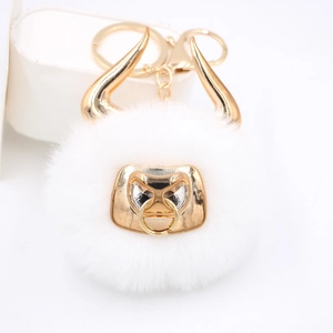 Detail of a white faux fur bull keychain featuring golden horns and a metallic bull mask