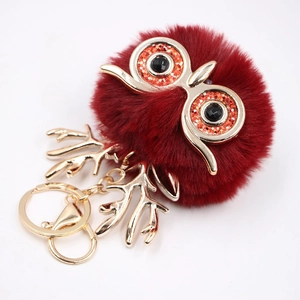Gros plan d'un porte-clés hibou en peluche rouge avec des breloques métalliques dorées