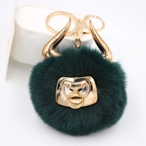 Detail shot of a dark green plush bull head keychain with gold horns and metal ring