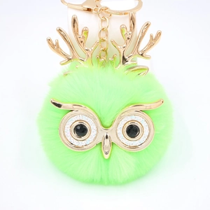 Détail du porte-clés hibou en fausse fourrure verte avec bois dorés et yeux noirs brillants