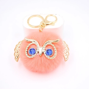 Détail de porte-clés hibou en fausse fourrure avec cadre en or et yeux en pierres bleues