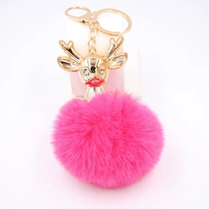 Détail d'un porte-clés cerf avec tête dorée et pompon en peluche rose vif élégant